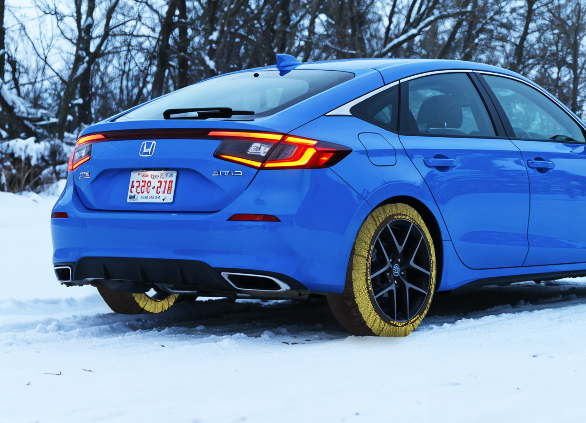 Honda azul equipado con fundas de nieve en las ruedas, en un entorno nevado.